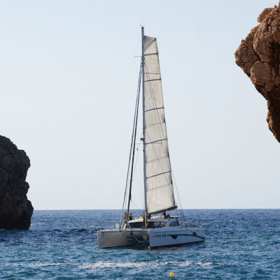 Sailboat on the sea between two rocky cliffs under a clear sky.